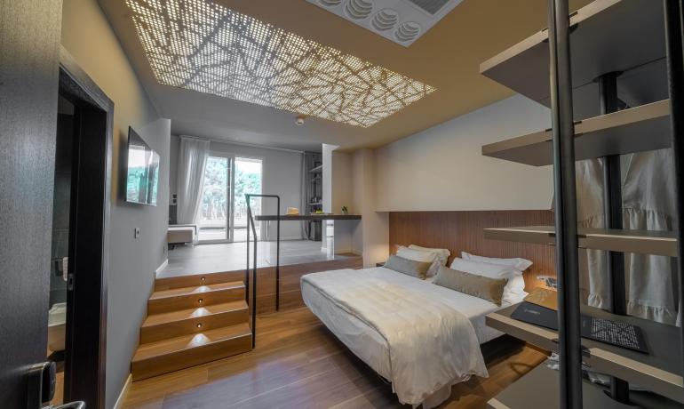 Modern room with bed, decorative ceiling, and balcony.