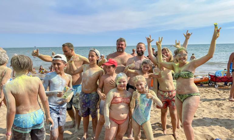 Happy group on the beach, covered in colorful powder.