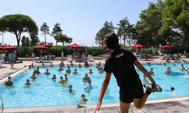 Aquagym class in pool with instructor and participants.