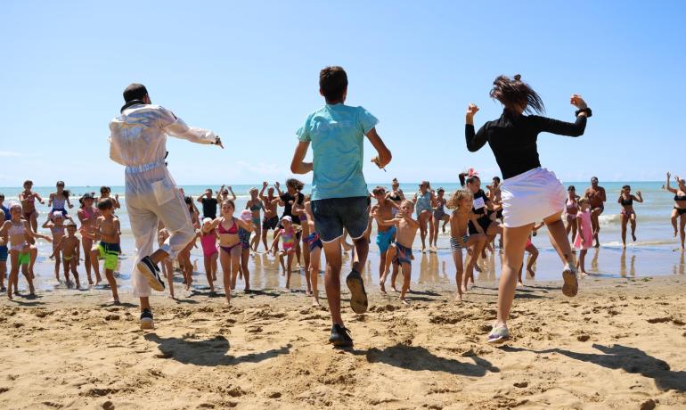 Group of people dancing on the beach under the sun.